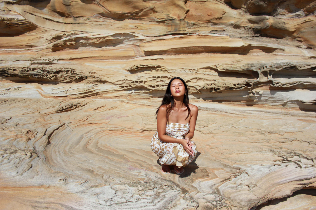Oh So Troppy Female model seated infront of natural sandstone backdrop